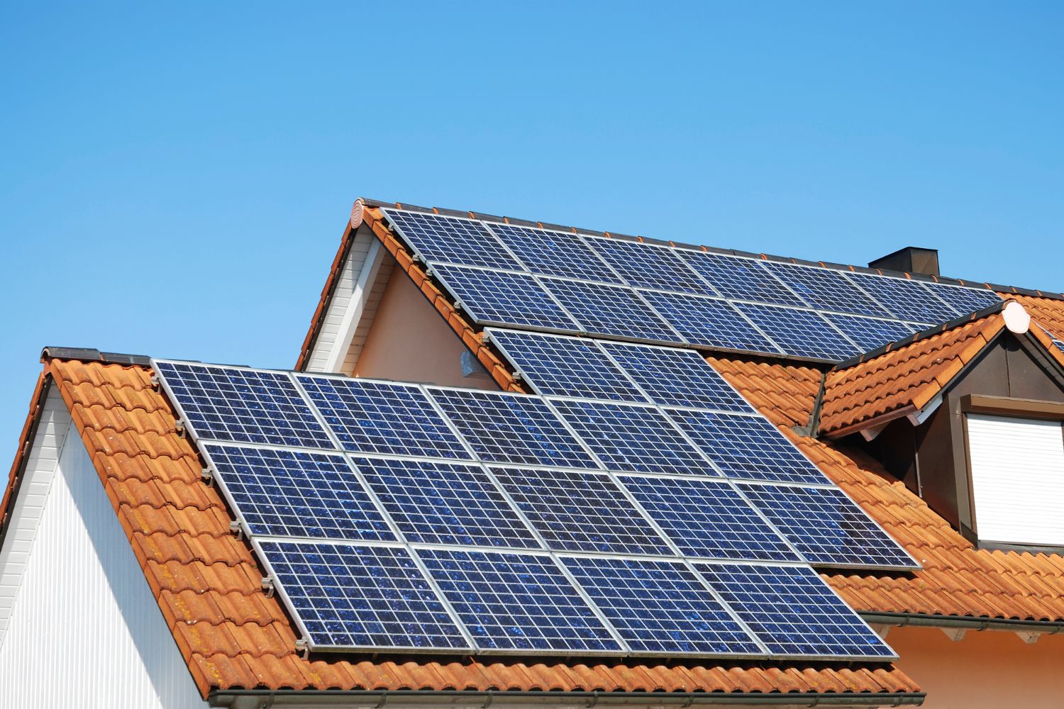 Eine Photovoltaikanlage auf einem Hausdach und blauer Himmel.